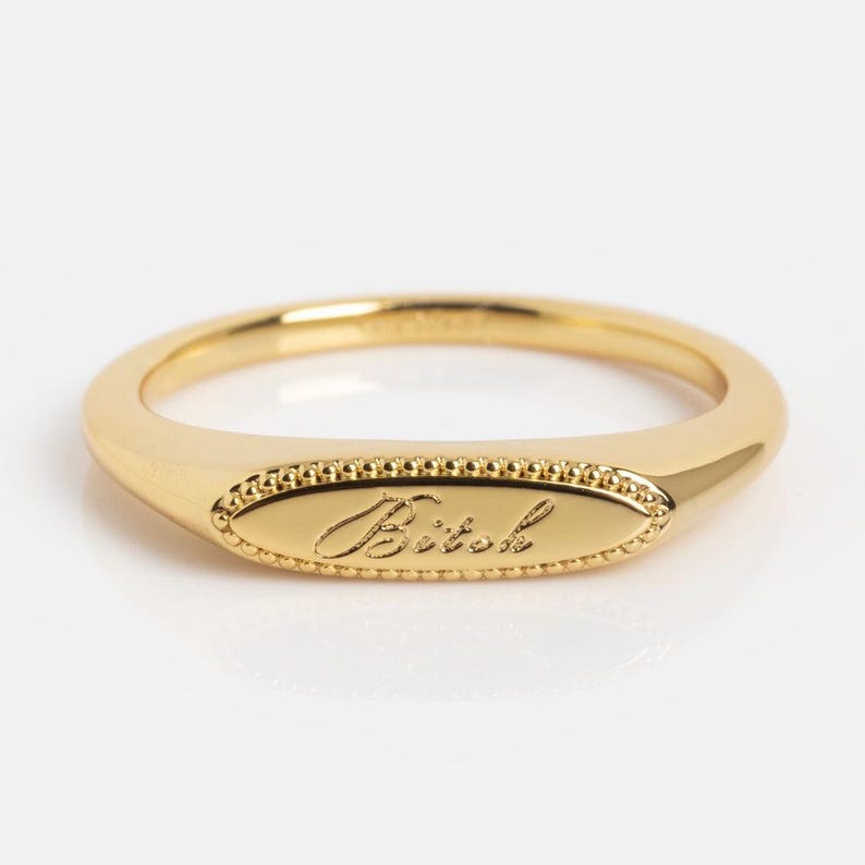 14K solid gold Tiny Bitch signet ring featuring elegant cursive engraving on a petite signet face with vintage milgrain border and 1.2mm band, minimalist stacking ring, engraved statement jewelry, modern heirloom ring, dainty gold signet, available in yellow gold, white gold, rose gold, sterling silver, gold vermeil, and gold plated brass.