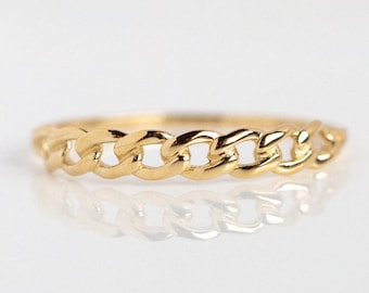 Könnte beinhalten: Ein goldener Kettenring mit poliertem Finish. Der Ring hat ein durchgehendes Kettenglied-Design, das Licht reflektiert. Der Ring wird auf einer reflektierenden Oberfläche präsentiert, was sein Aussehen verbessert. Der Schmuck ist ein schlichtes, aber elegantes Accessoire.