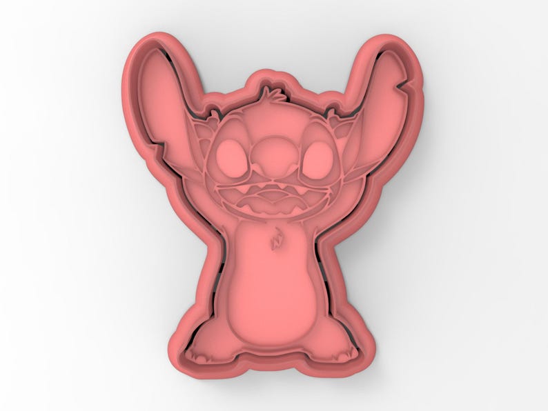 May include: Pink plastic cookie cutter shaped like Stitch from the Disney movie Lilo & Stitch. Stitch is standing with his arms raised and has a mischievous expression on his face.