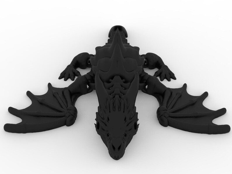 May include: A black dragon figurine with outstretched wings, claws, and a detailed head. The dragon is lying flat, showcasing its intricate design. The figurine is a solid, dark color, and appears to be made of a hard material.