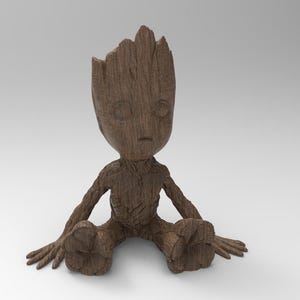 Puede incluir: Una figura de madera marrón de un personaje con apariencia de árbol, sentado con los brazos y las piernas extendidos. La figura tiene una textura detallada, con una cabeza en forma de copa de árbol. La figura está sobre un fondo blanco liso.