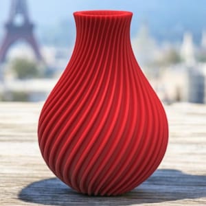 May include: A red, swirl-patterned ceramic vase with a rounded base and a narrow opening.