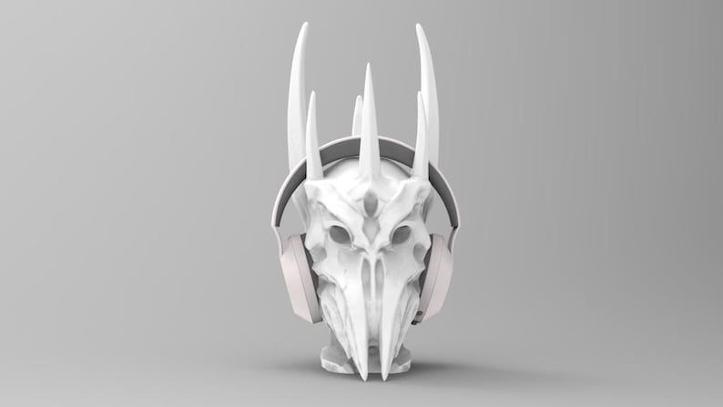 May include: White 3D printed skull with horns wearing white headphones. The skull has a detailed design with sharp edges and a pointed chin.