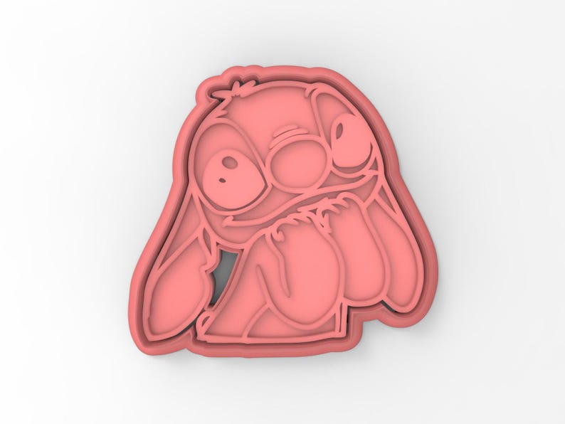 May include: Pink plastic cookie cutter shaped like Stitch from the Disney movie Lilo & Stitch. Stitch is shown with his signature blue eyes and a mischievous expression.