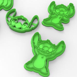 Peut inclure: Ensemble de quatre emporte-pièces en plastique vert en forme de Stitch du film Disney Lilo & Stitch. Les emporte-pièces sont dans différentes poses, notamment debout avec les bras levés, debout avec les bras le long du corps et un gros plan du visage de Stitch.