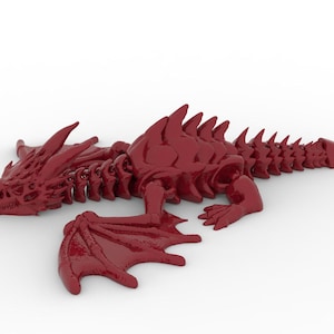 May include: A glossy, deep red dragon figurine with detailed scales, wings, and a spiky spine. The dragon is lying down, with its wings spread out. The figurine is a fantasy-themed decorative item.