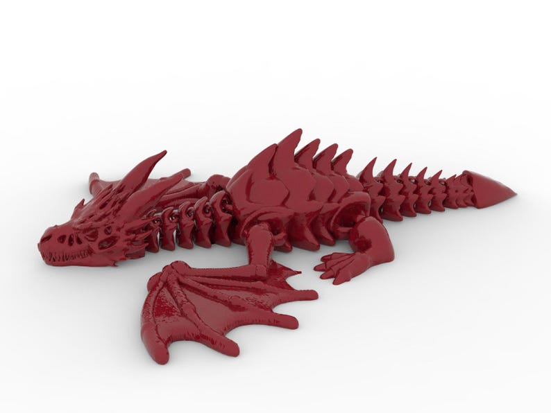 May include: A glossy, deep red dragon figurine with detailed scales, wings, and a spiky spine. The dragon is lying down, with its wings spread out. The figurine is a fantasy-themed decorative item.
