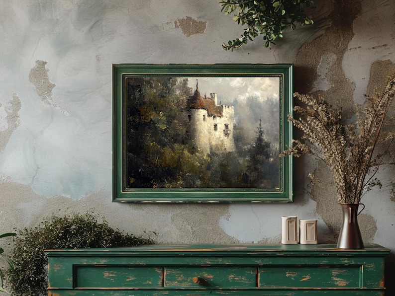 Op de afbeelding: Een ingelijst schilderij van een wit kasteel met een rood dak, omringd door bomen en mist. Het schilderij is in een groene lijst en hangt aan een muur.