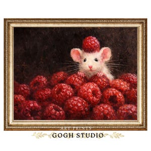 May include: A framed art print featuring a white mouse peeking out from a pile of red raspberries, with one berry balanced on its head. The artwork has a dark background and is framed in a gold-colored ornate frame. The text "ART PRINTS" and "GOGH STUDIO" are at the bottom.