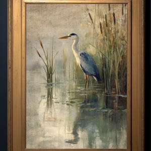 May include: A framed oil painting of a grey heron standing in a pond with reeds in the background. The heron is facing left and has its head turned to the right. The water is a light blue-green color and the reeds are a dark green color.