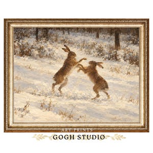 Puede incluir: Una impresión artística enmarcada que representa a dos liebres marrones de pie sobre sus patas traseras boxeando en un campo cubierto de nieve. La escena muestra un paisaje invernal con árboles al fondo. El texto ART PRINTS GOGH STUDIO aparece debajo.