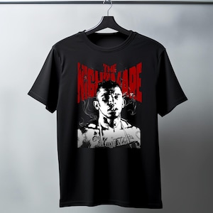 May include: Black t-shirt featuring a black and white portrait of a person with tattoos, smoking. The text "THE NIGHTMARE" is in red above the portrait. The shirt is hanging on a black hanger.