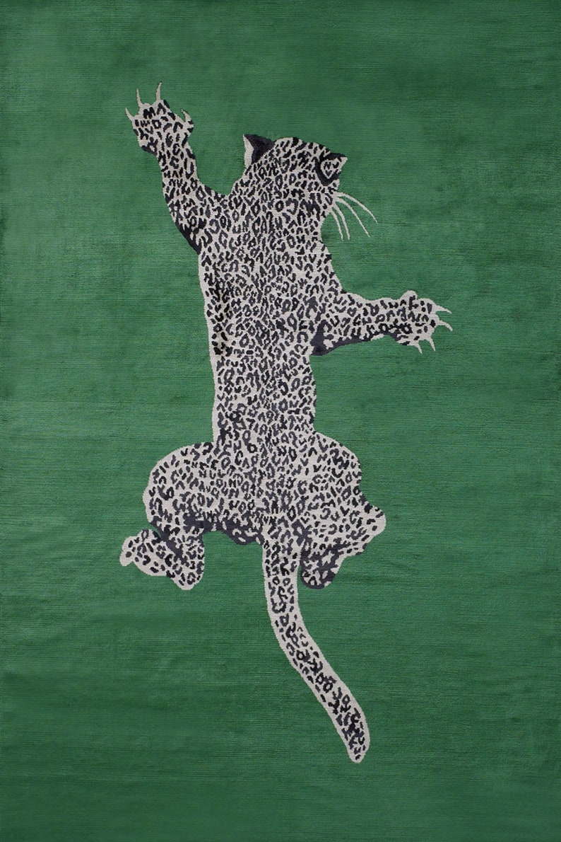 Pu&ograve; includere: Un tappeto verde con un design a leopardo stilizzato. Il leopardo &egrave; raffigurato con macchie bianche e nere, con le zampe anteriori sollevate. Il tappeto ha uno sfondo verde unito.