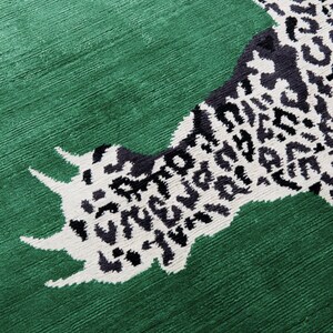 Pu&ograve; includere: Un tappeto verde con un design sorprendente. Il tappeto presenta una grande impronta stilizzata in un motivo leopardato bianco e nero. Lo sfondo &egrave; verde pieno e strutturato.