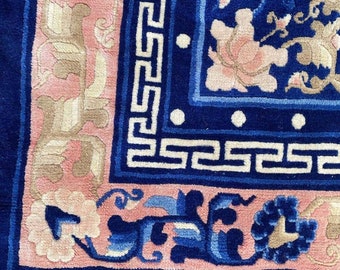 May include: A blue and pink rug with a floral pattern and a white border. The rug has a fringe on the bottom.