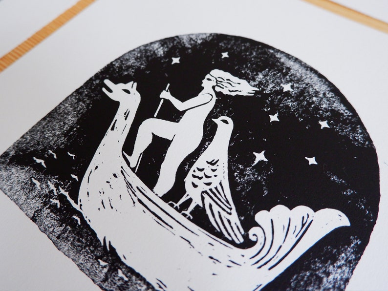 Peut inclure: Gravure sur linol&eacute;um en noir et blanc d'une femme chevauchant un bateau avec un oiseau. La femme a les cheveux longs et tient un b&acirc;ton. Le bateau a la forme d'un cygne et a un oiseau &agrave; l'arri&egrave;re. L'arri&egrave;re-plan est bleu fonc&eacute; avec des &eacute;toiles blanches.