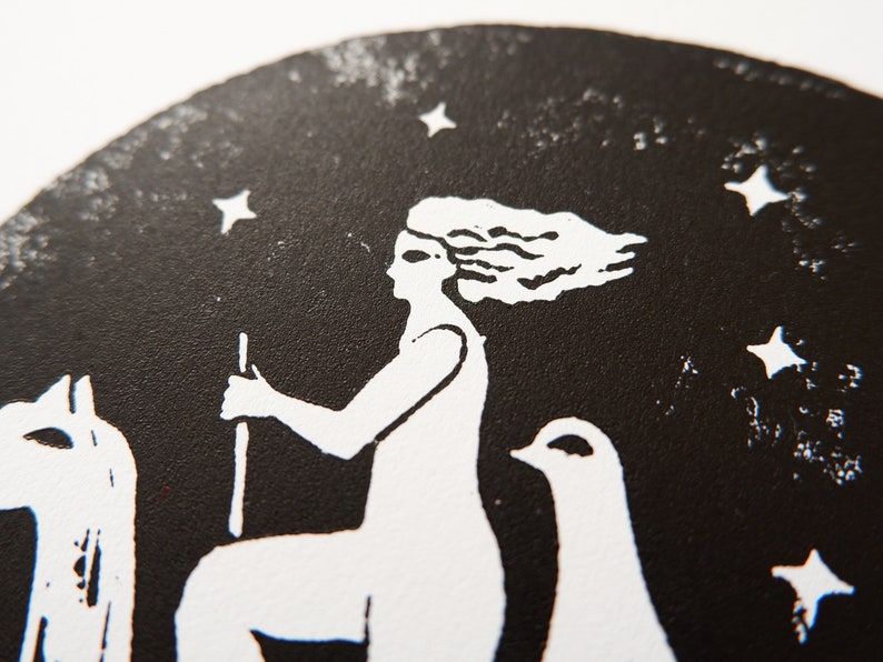 Peut inclure: Gravure sur linol&eacute;um en noir et blanc d'une femme &agrave; cheval avec un oiseau &agrave; ses c&ocirc;t&eacute;s, sur fond de ciel &eacute;toil&eacute;.