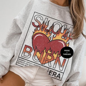 May include: Gray sweatshirt with a graphic print of a heart on fire with the text "Slow Burn Era" and "Prose + Threads".