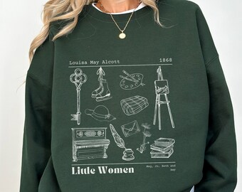 Könnte beinhalten: Ein dunkelgrüner Pullover mit einem weißen Grafikdruck von Illustrationen, die sich auf das Buch "Little Women" von Louisa May Alcott beziehen. Die Grafik enthält einen Schlüssel, Schlittschuhe, eine Farbpalette, einen Hut, ein Klavier, eine Feder und Bücher. Der Text "Little Women" und "Louisa May Alcott 1868" ist ebenfalls in der Grafik enthalten.