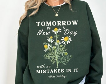 May include: Green sweatshirt with a white graphic print that says "Tomorrow is a New Day with no Mistakes in it -Anne Shirley-." The graphic also features a white daisy flower with a yellow center.