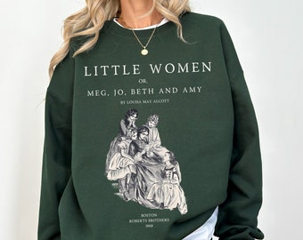Könnte beinhalten: Ein dunkelgrüner Pullover mit einem weißen Grafikdruck des Buchcovers von "Little Women" von Louisa May Alcott. Das Buchcover zeigt eine Schwarzweißillustration von vier Mädchen.