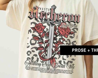May include: A cream-colored oversized t-shirt with a graphic print of a sword, roses, and a leopard print pattern. The text "NESTA Archeron Lady Death Nothing Can Break Me" is printed on the shirt.