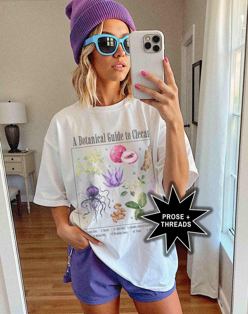 May include: A white t-shirt with a botanical illustration and the text "A Botanical Guide to Cleocal". The model is wearing a purple beanie and blue sunglasses.