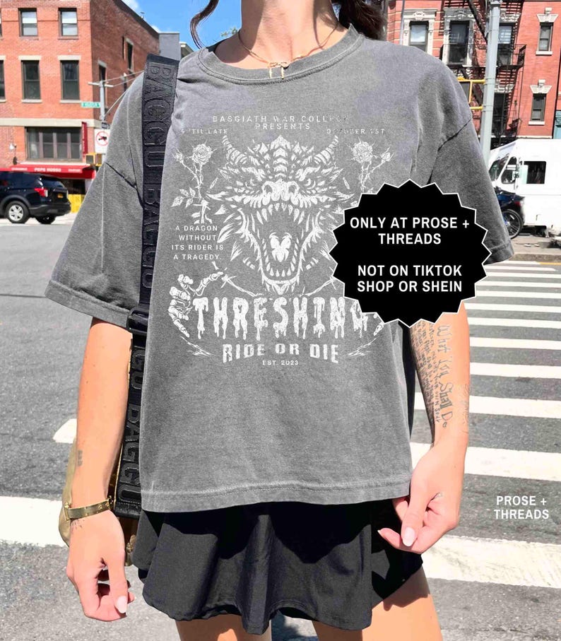 May include: Gray graphic t-shirt featuring a white dragon design with the text "THRESHING RIDE OR DIE EST. 2023". The shirt also includes the text "A DRAGON WITHOUT ITS RIDER IS A TRAGEDY".