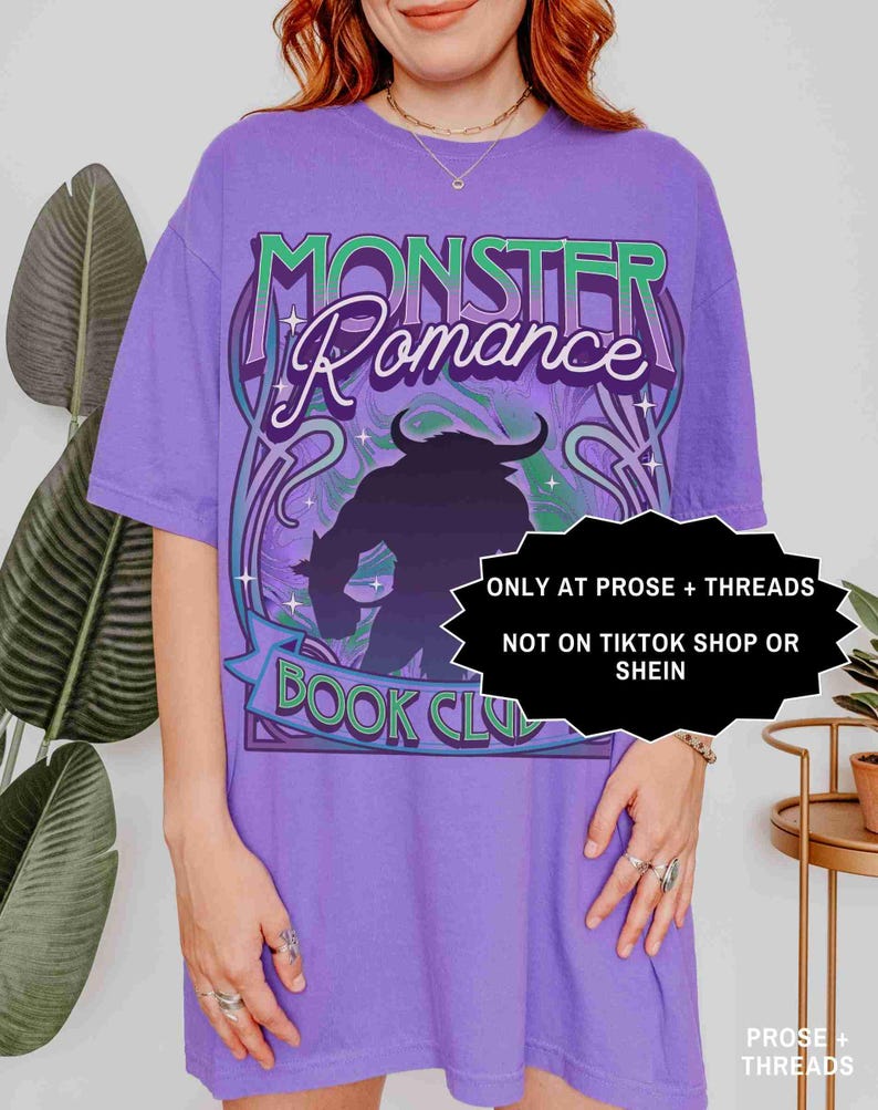 Op de afbeelding: Een paars T-shirt met de tekst "MONSTER Romance BOOK CLUB" in een gestileerd ontwerp. Het shirt heeft een silhouet van een monster en de tekst "ONLY AT PROSE + THREADS NOT ON TIKTOK SHOP OR SHEIN".