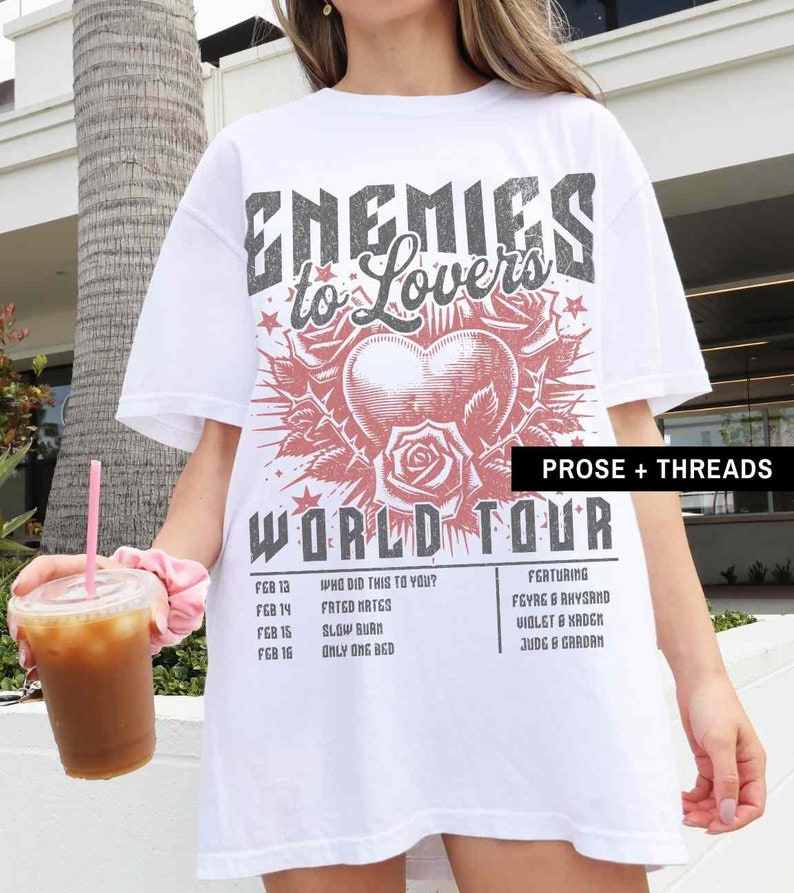 Pode incluir: Camiseta branca oversized com uma estampa gr&aacute;fica de um cora&ccedil;&atilde;o com rosas e o texto "Enemies to Lovers World Tour". O texto "Who Did This To You?" e uma lista de datas e atos musicais s&atilde;o impressos na parte inferior da camiseta.