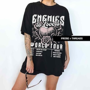 Pode incluir: Camiseta preta com uma estampa gr&aacute;fica branca de um cora&ccedil;&atilde;o com espinhos e uma rosa. O texto "Enemies to Lovers World Tour" est&aacute; impresso na camiseta. As datas da turn&ecirc; e os artistas em destaque est&atilde;o listados abaixo do gr&aacute;fico.