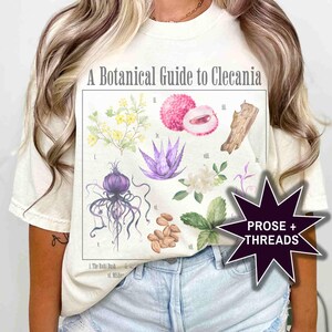May include: A white t-shirt with a botanical illustration of plants and fruits. The illustration is titled "A Botanical Guide to Clecania". The text "PROSE + THREADS" is in a starburst shape in the bottom right corner.