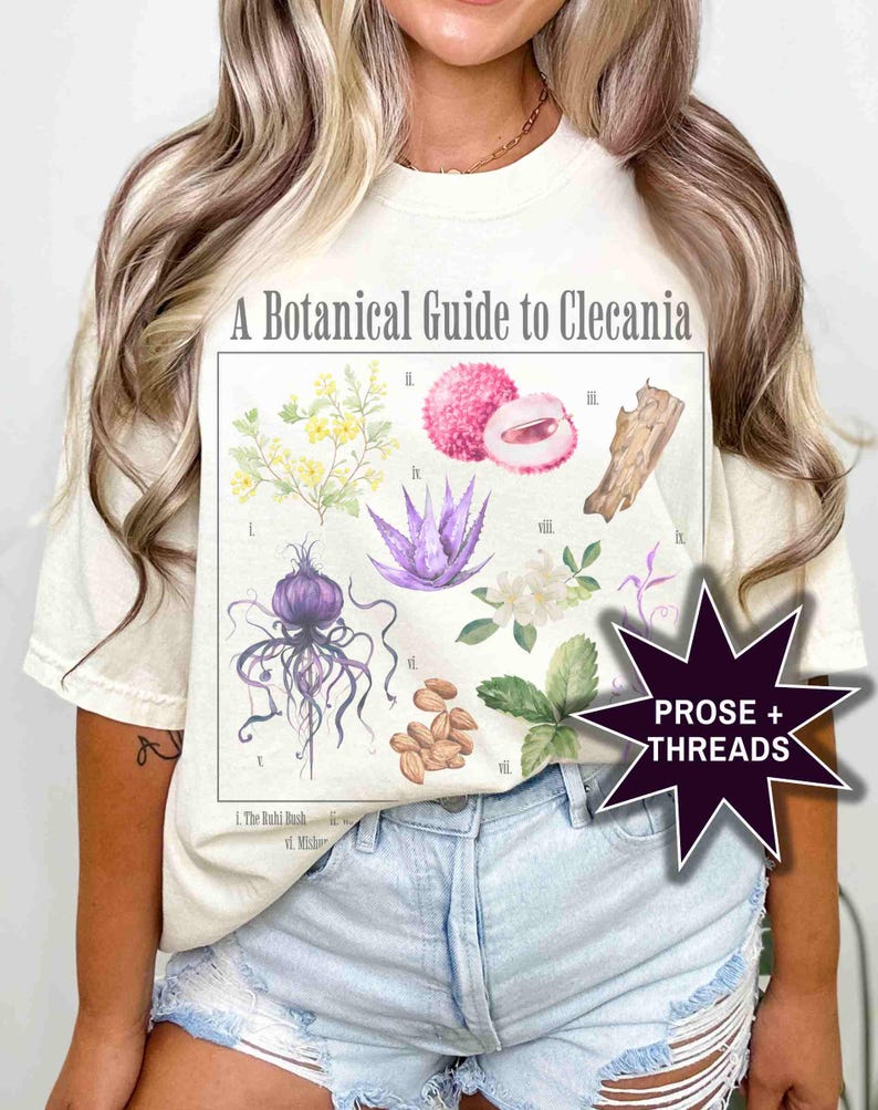 May include: A white t-shirt with a botanical illustration of plants and fruits. The illustration is titled "A Botanical Guide to Clecania". The text "PROSE + THREADS" is in a starburst shape in the bottom right corner.