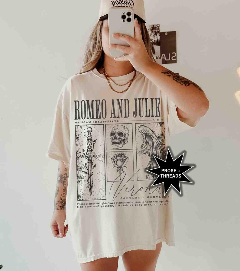 May include: Cream-colored t-shirt featuring the text "ROMEO AND JULIE" with illustrations of a sword, skull, rose, and wings. The shirt also includes the text "Verona" and a quote from William Shakespeare.