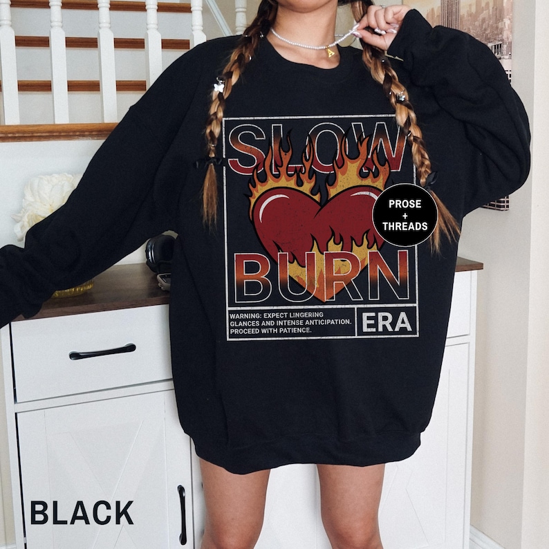 May include: Black sweatshirt with a graphic print of a heart on fire with the text "SLOW BURN ERA" and "PROSE + THREADS".