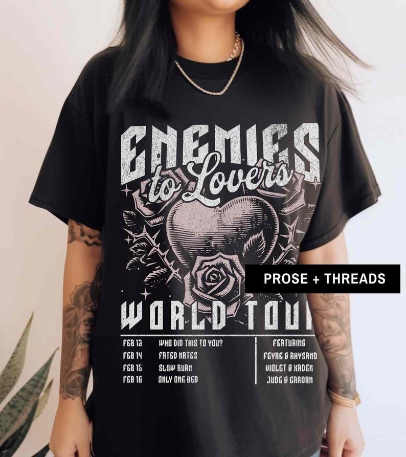 Pode incluir: Camiseta preta com uma estampa gr&aacute;fica de um cora&ccedil;&atilde;o com espinhos e uma rosa. O texto "Enemies to Lovers" &eacute; impresso acima do gr&aacute;fico e "World Tour" &eacute; impresso abaixo. As datas e os nomes da turn&ecirc; s&atilde;o listados abaixo do gr&aacute;fico.