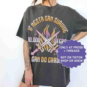 May include: Pepper-colored graphic tee with the text "IF NESTA CAN SURVIVE 10,000 STEPS CAN DO GARD." The design includes crossed swords and flames. Additional text reads "ONLY AT PROSE + THREADS" and "NOT ON TIKTOK SHOP OR SHEIN."