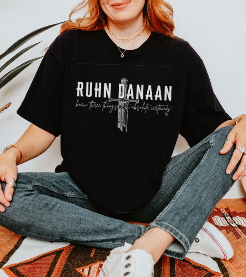 May include: Black t-shirt with a white graphic design featuring a sword and the text "RUHN DANAAN knew three things with absolute certainty."