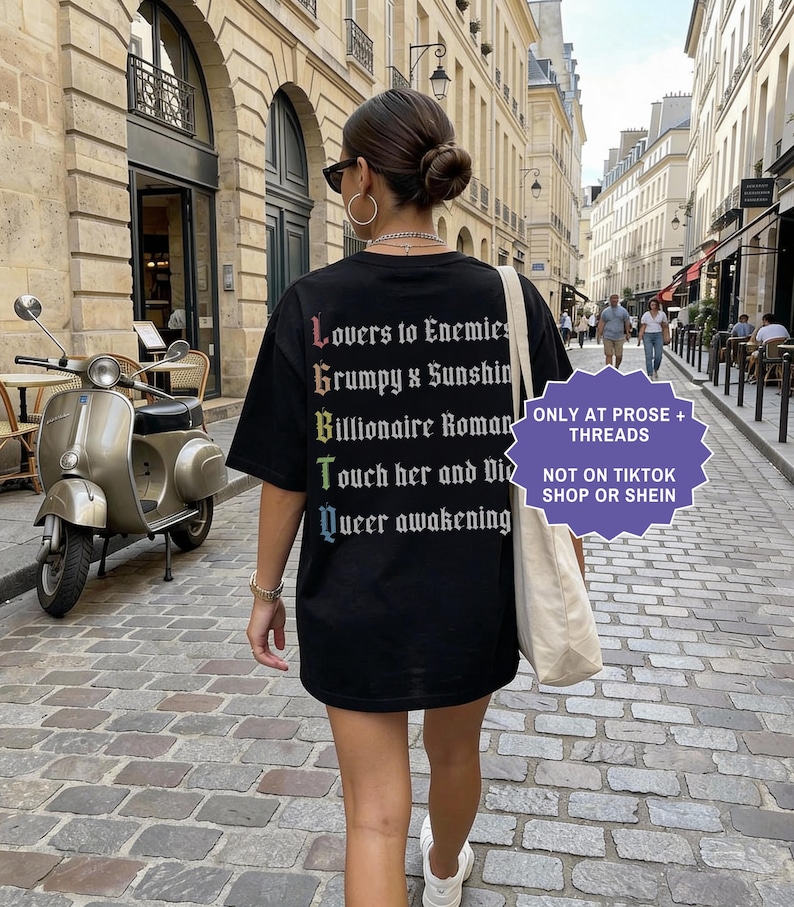 Pu&ograve; includere: Una t-shirt nera con testo bianco sul retro che recita: Lovers to Enemies, Grumpy x Sunshine, Billionaire Romance, Touch her and Die, Queer awakening. La prima lettera di ogni riga forma LGBTQ in colori arcobaleno.