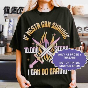 May include: Black graphic t-shirt with the text "IF NESTA CAN SURVIVE 10,000 STEPS I CAN DO CARDIO". The design includes crossed swords and a flame graphic. A purple and white sticker reads "ONLY AT PROSE + THREADS NOT ON TIKTOK SHOP OR SHEIN".