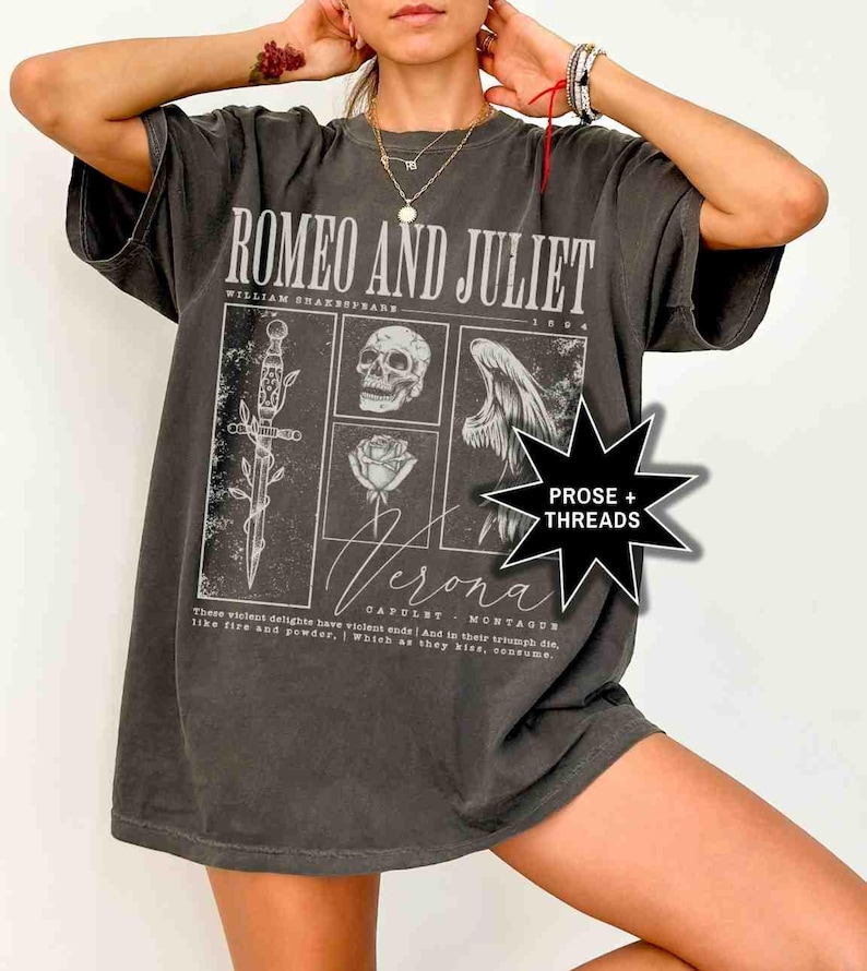 May include: Dark gray t-shirt featuring the text "ROMEO AND JULIET" above a graphic design with a sword, skull, rose, and angel wing. The shirt also includes the word "Verona" and a quote from the play.