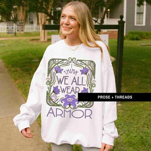 May include: White sweatshirt with a graphic print of flowers and the text "I think we all wear armor".
