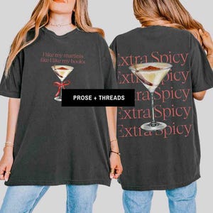 May include: Dark gray t-shirt with a martini graphic and the text "I like my martinis like I like my books" on the front. The back of the shirt features a martini graphic and the words "Extra Spicy" repeated.
