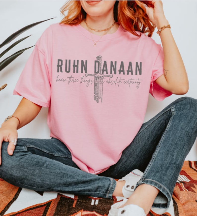 May include: Pink t-shirt featuring a graphic of a sword and the text "RUHN DANAAN knew three things with absolute certainty".