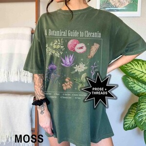 May include: A green oversized t-shirt with a botanical illustration and the text "A Botanical Guide to Clecania".