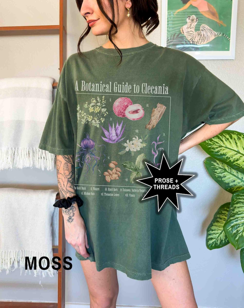 May include: A green oversized t-shirt with a botanical illustration and the text "A Botanical Guide to Clecania".