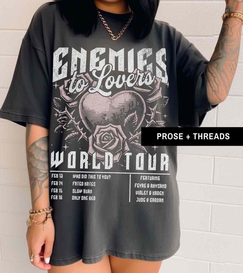 Pode incluir: Uma camiseta preta com uma estampa gr&aacute;fica de um cora&ccedil;&atilde;o com espinhos e rosas. O texto "Enemies to Lovers World Tour" est&aacute; impresso na camiseta. O texto "Featuring Feyre & Rhysand, Violet & Xaden, Jude & Cardan" est&aacute; impresso no lado direito da camiseta. O texto "Who did this to you? Fated Mates, Slow Burn, Only One Bed" est&aacute; impresso no lado esquerdo da camiseta.