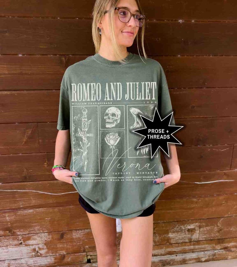 May include: Olive green t-shirt featuring the text "ROMEO AND JULIET" above a graphic design with a skull, rose, and sword. The shirt also includes the text "Verona" and "PROSE + THREADS".