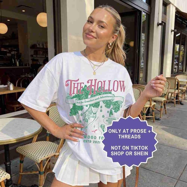 Pu&ograve; includere: T-shirt bianco con grafica "The Hollow" in rosa e verde, con un'illustrazione di una mappa. La maglietta &egrave; abbinata a una gonna a pieghe bianca. &Egrave; visibile anche il testo "ONLY AT PROSE + THREADS" e "NOT ON TIKTOK SHOP OR SHEIN".