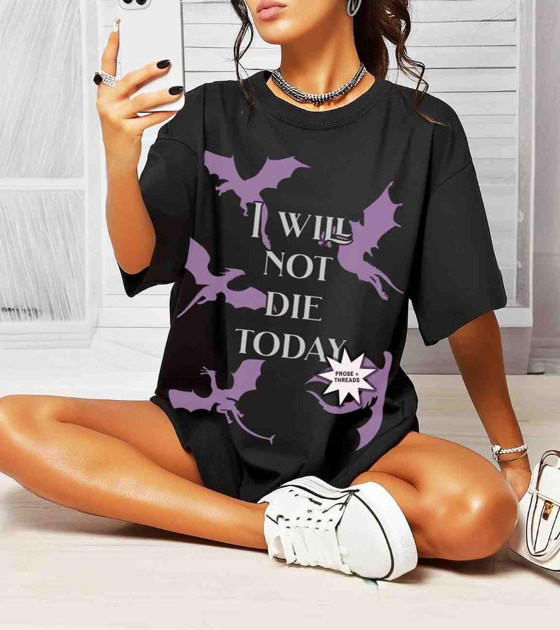 May include: Black oversized t-shirt with a graphic print of purple dragons and the text "I Will Not Die Today".